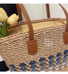 Close-up of hand-woven straw tote with colorful patterns and reinforced leather handle