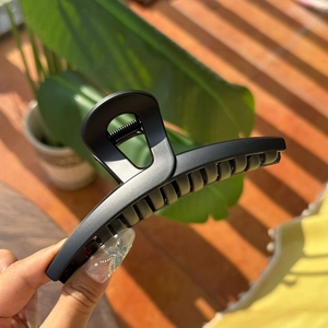 Detail of matte black 13.5cm butterfly hair claw clip with cutout design in hand