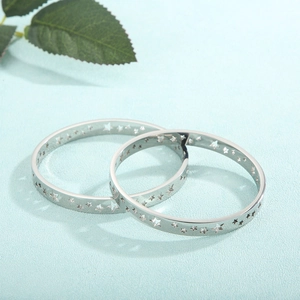 Macro view of silver star patterned bangles with hollow pentagram cutouts on blue fabric