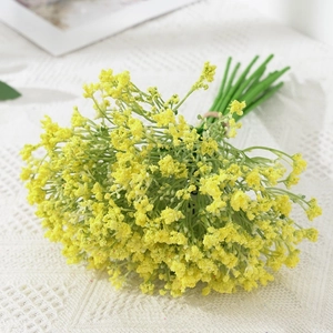 Macro view of artificial yellow baby's breath flowers on white crochet tablecloth