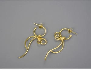 Detailed close-up of S925 sterling silver stamp on golden bow ribbon drop earrings