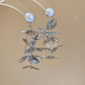 Detailed close-up of silver leaf tassels with white pearl inlay on luxury earrings