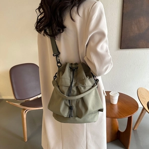 Détail du sac seau en nylon vert armée avec cordon de serrage porté par un mannequin