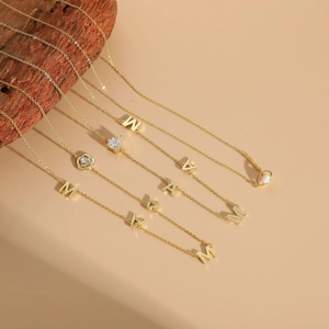 Close-up of golden MAMA letter charms with heart zircon and opal pendant necklace