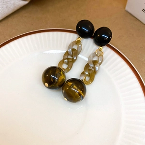 Detailed macro view of vintage resin chain earrings with tiger eye stone beads on a tray