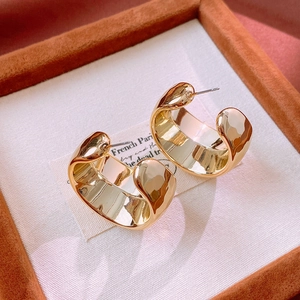 Close-up of polished gold wide-hoop C-shaped earrings in a premium jewelry gift box