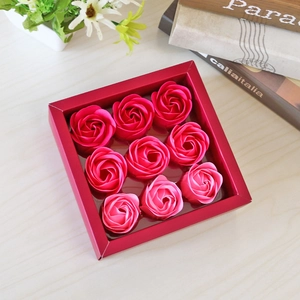 Detail view of a square red gift box containing nine artificial soap roses on a wooden desk
