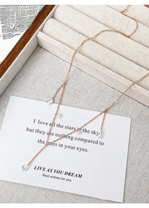 Detailed view of rose gold zircon tassel necklace with water drop pendants on beige tray