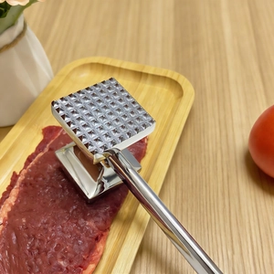 Dual-sided stainless steel meat mallet tool for steak tenderizing on wooden tray