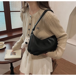 Detail of black PU leather crescent bag featuring a cute white plush bear charm accessory