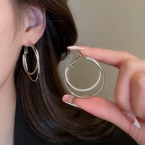 Macro detail of silver double hoop earrings featuring polished and textured finishes