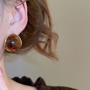 Close-up of amber resin earrings with gold edges on model for a retro aesthetic