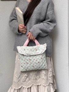 Detailed view of quilted laptop sleeve with lace trim and floral rabbit pattern