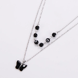 Detail of silver double layer necklace with black butterfly pendant and evil eye pattern beads