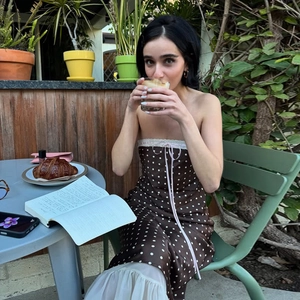 Polka dot strapless satin dress with lace trim detail worn by model at an outdoor cafe