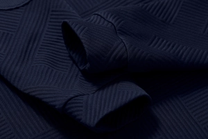 Macro view of dark blue geometric textured fabric and stitched sleeve cuff on men hoodie