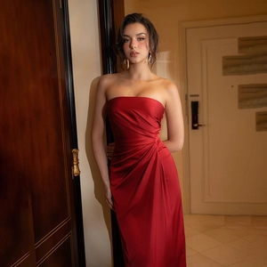 Detailed view of red satin strapless dress featuring side pleats and elegant slim fit