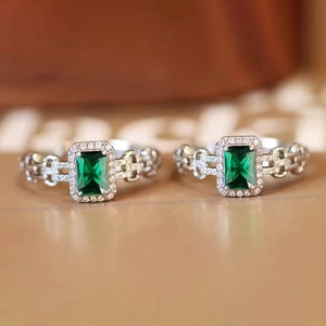 Dettaglio macro dell'anello con gemma verde taglio smeraldo, diamanti e fascia a catena