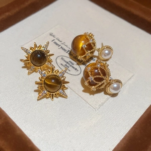 Macro shot of 18K gold plated tiger eye earrings with pearls in a jewelry box
