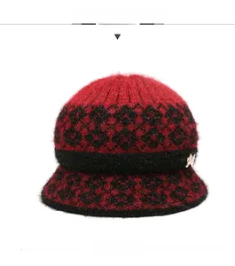 Front view of a warm red knit wool bucket hat with black floral pattern and gold bow
