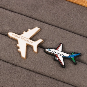 3D airplane enamel pins with World Traveler text on dark velvet jewelry display