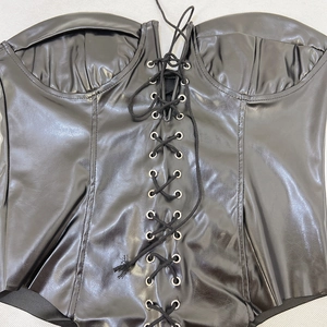 Detail of black PU leather tube jumpsuit featuring silver eyelets and lace-up front design