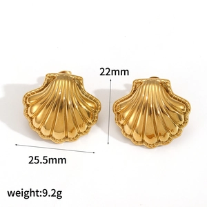 Close-up of golden shell-shaped earrings with striped texture and size dimensions