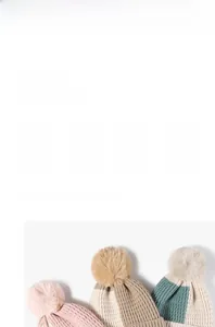 Détail de bonnets en maille épaisse avec pompons en rose, beige et gris clair
