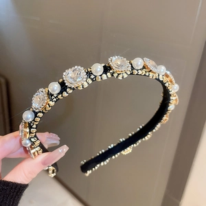 Detailed shot of pearls and square crystals set on a black fabric headband with gold accents