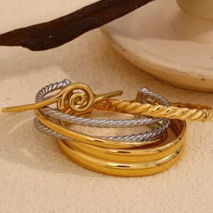 Stacked gold and silver stainless steel bangles with twisted and spiral textured designs