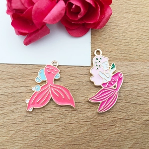 Detail of colorful mermaid and fishtail enamel charms on a rustic wooden background
