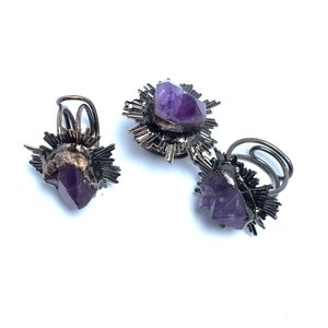 Macro shot of three vintage gothic rings featuring raw purple amethyst and sunburst metal