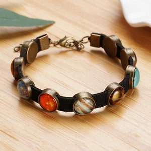 Close-up of retro punk bracelet featuring multi-layer black leather and planet pendant