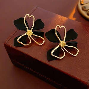 Detail of hollow double-layer black flower earrings with gold edges on leather box