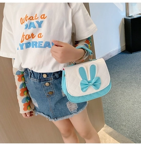 Blue and white girl's handbag with rabbit ears and bow decoration held by a model