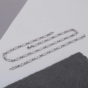 Detail of silver stainless steel cross link chain necklace on a dark stone background