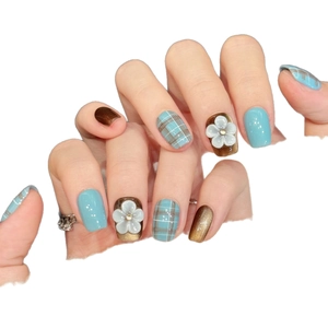 Handmade press-on nails with blue-green plaid and 3D white floral accents on brown glitter