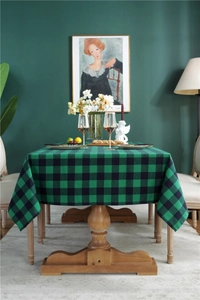 Detail of red and green plaid festive tablecloth draped over a dining table setup