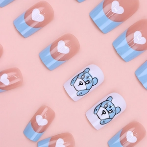 Close-up of blue and pink French press-on nails with white hearts and cartoon puppy art