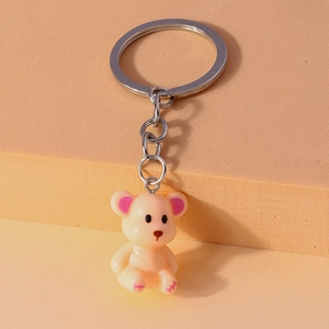 Close-up of cute beige bear keychain with pink glitter ears on a minimal display stand