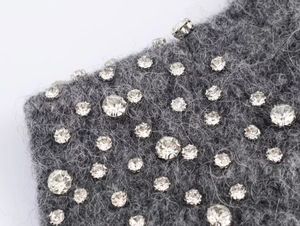 Macro shot of sparkling rhinestones and crystal beads on a dark gray wool knit fabric surface