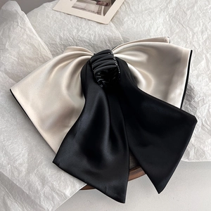 Close-up of elegant black and beige bow hair claw clip featuring premium satin texture