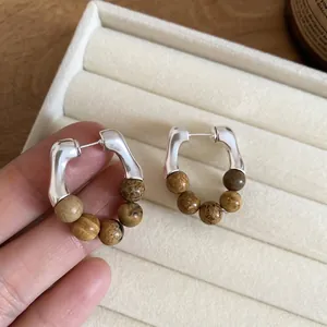 Boucles d'oreilles créoles avec perles de pierre marron sur un écrin à bijoux