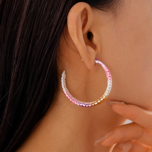 Detail of bohemian colorful woven fiber C-shape hoop earrings worn by a model