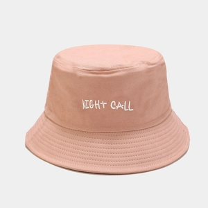 Close-up of NIGHT CALL embroidery on a light pink cotton bucket hat with stitched brim
