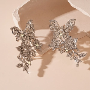 Detail von silbernen Quasten-Ohrringen mit Schmetterling-Blumen-Design und Strasssteinen