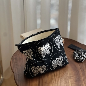 Vue détaillée du sac en toile noire avec broderie papillon blanc et étiquette tissée