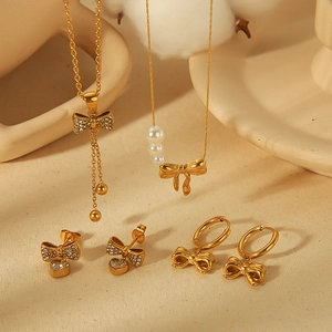 18k gold plated bow jewelry set with pearl necklace and heart stud earrings on beige cloth