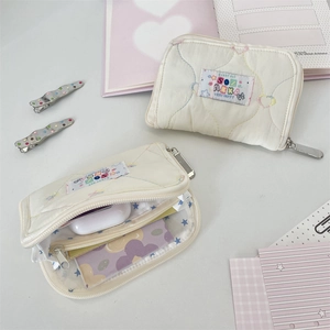 Close-up of cream quilted pouch with colorful embroidery and star pattern inner lining