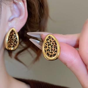 Detail shot of golden teardrop leaf earrings featuring stylish leopard print pattern